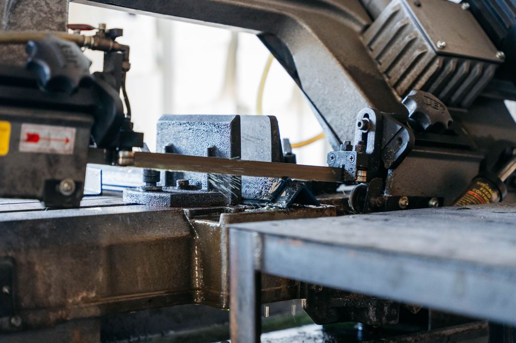 Horizontal bandsaw cutting steel bar stock in the Fresno shop