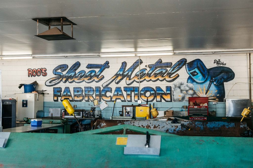 Shop interior with the hand-painted Sheet Metal Fabrication mural above the workbenches