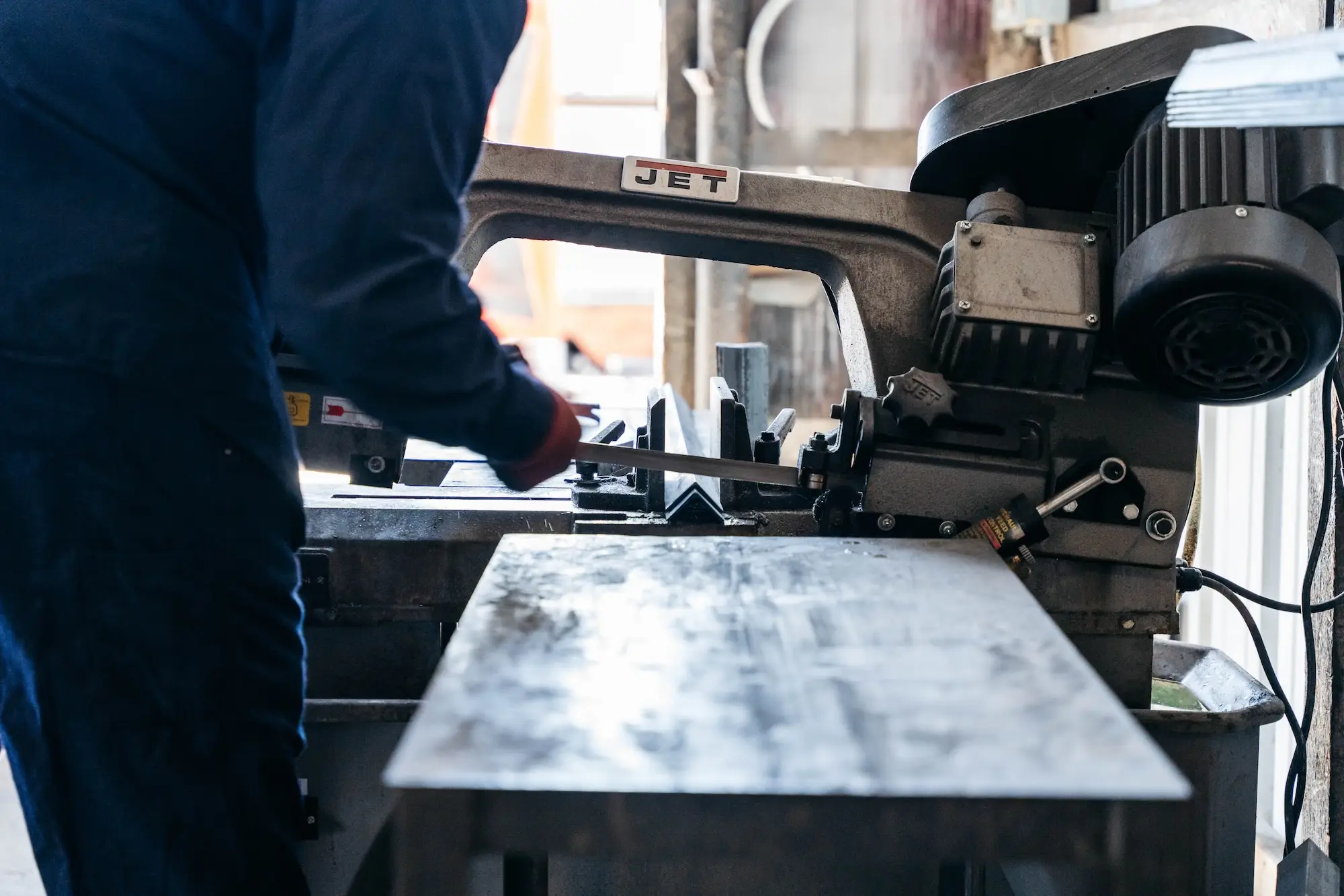 Metal bar being cut on a shop bandsaw
