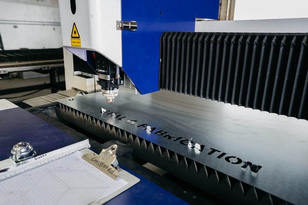 Fiber laser cutting head working a steel sheet on the cutting table